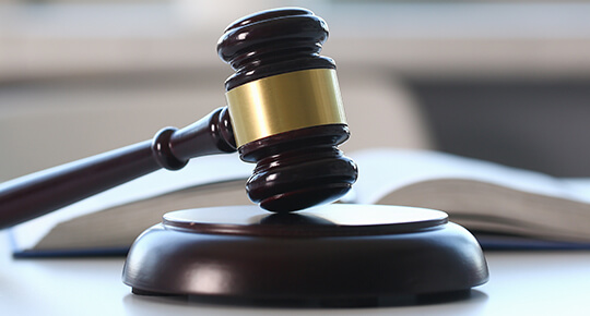 Close up of a gavel with open book in the background.